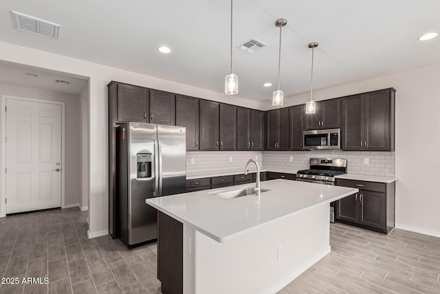 kitchen featuring dark brown cabinetry, stainless steel appliances, decorative light fixtures, and sink