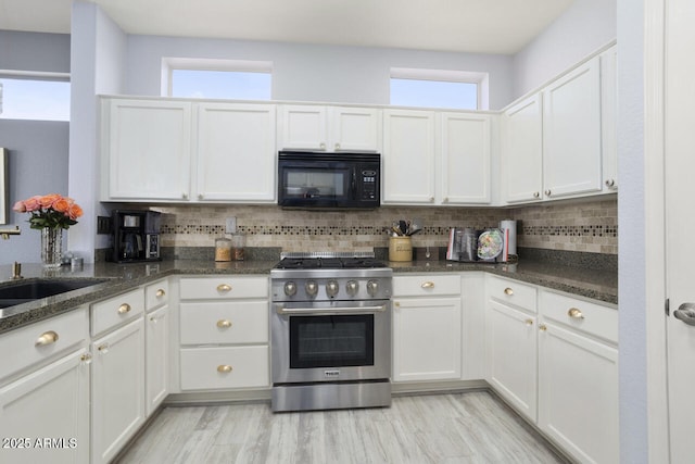 kitchen with white cabinets, tasteful backsplash, stainless steel range, and dark stone counters