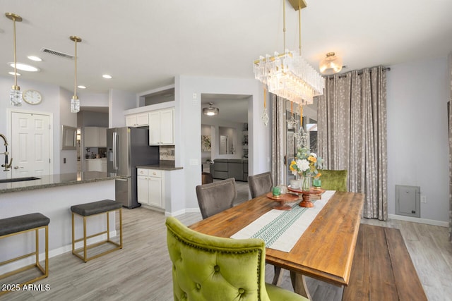 dining space with sink, a chandelier, and light wood-type flooring