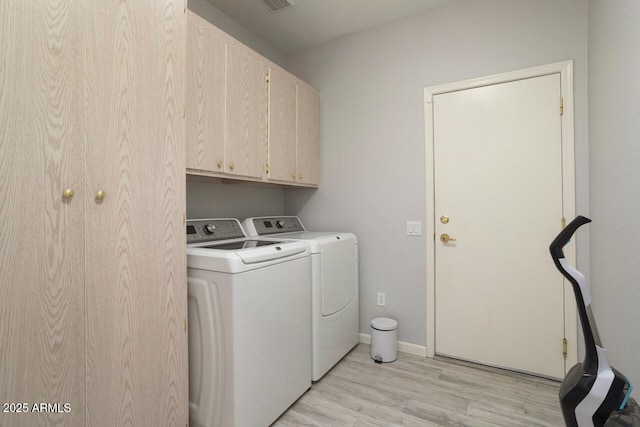 laundry room featuring washing machine and dryer, cabinets, and light wood-type flooring