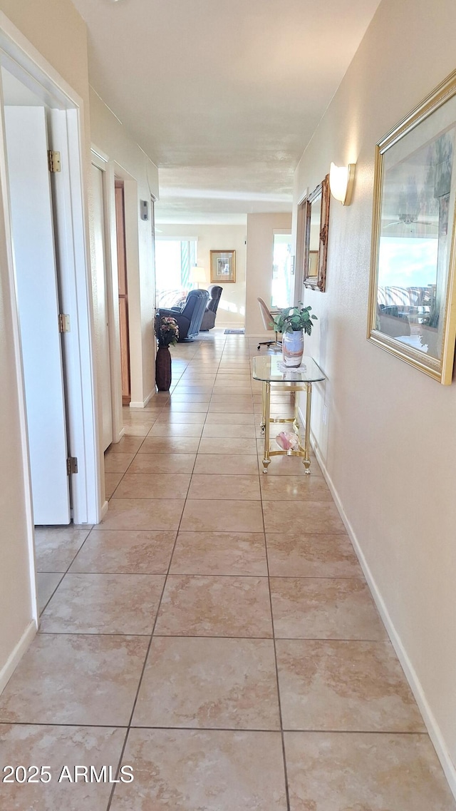 hall featuring light tile patterned floors and baseboards