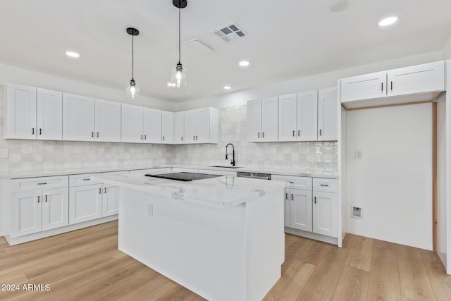 kitchen with a center island, white cabinets, light hardwood / wood-style flooring, decorative backsplash, and decorative light fixtures