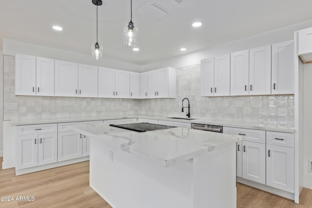 kitchen with white cabinets, light hardwood / wood-style floors, decorative light fixtures, and a kitchen island