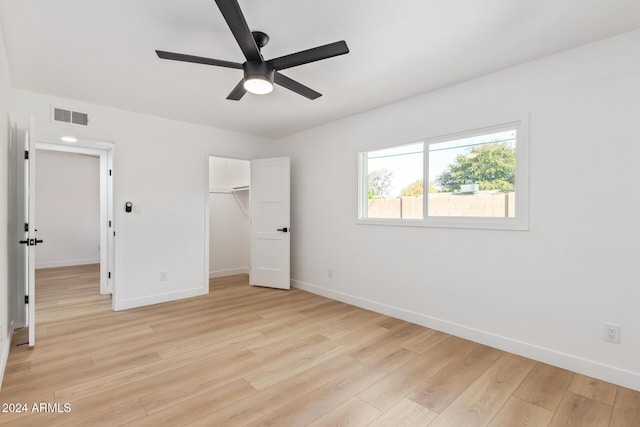 unfurnished bedroom featuring a closet, ceiling fan, light hardwood / wood-style flooring, and a spacious closet