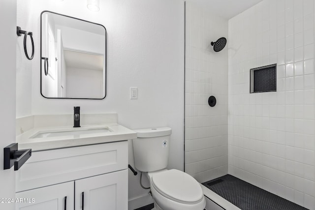 bathroom with tiled shower, vanity, and toilet