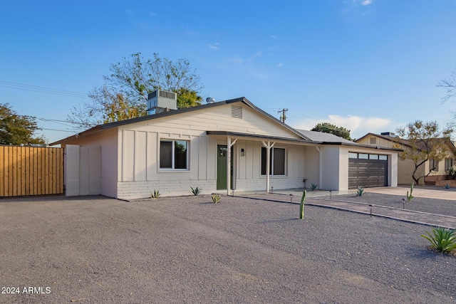 view of front of home with a porch, a garage, and central air condition unit