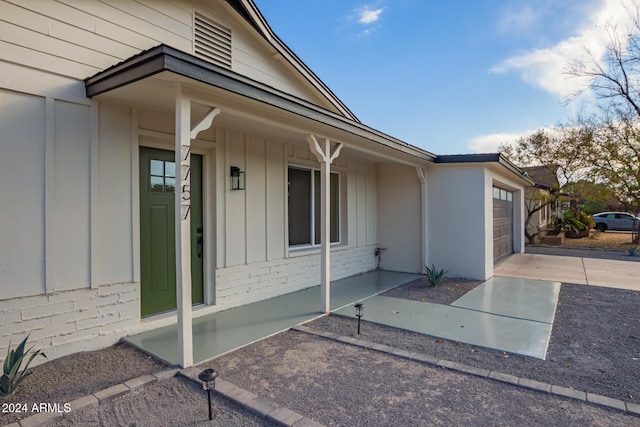 view of exterior entry featuring a porch and a garage