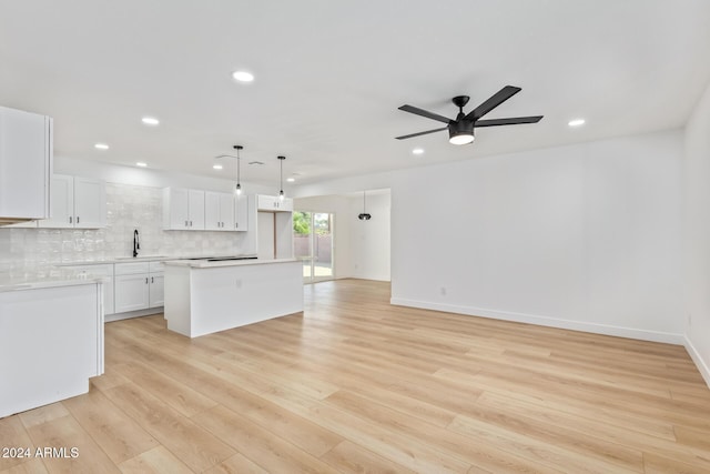 kitchen featuring pendant lighting, a center island, white cabinets, sink, and light hardwood / wood-style floors