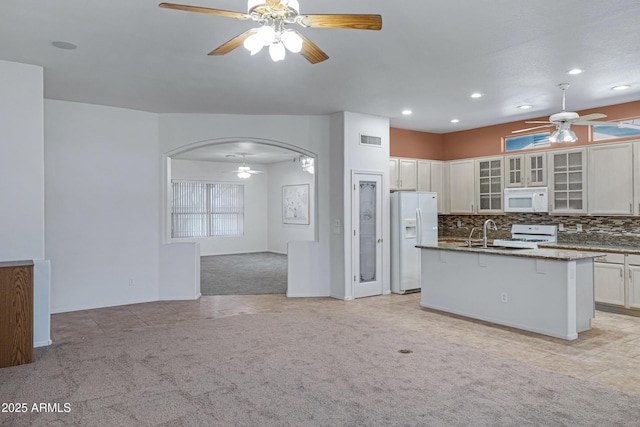 11413 S Coolwater Dr, Goodyear, AZ 85338 - kitchen featuring a ceiling fan, tasteful backsplash, dark stone counters, white appliances, and light colored carpet