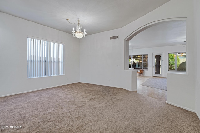 11413 S Coolwater Dr, Goodyear, AZ 85338 - empty room with baseboards, visible vents, an inviting chandelier, arched walkways, and light carpet