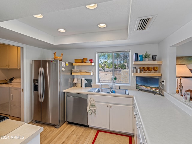 kitchen featuring white cabinetry, stainless steel appliances, a raised ceiling, sink, and washer and clothes dryer