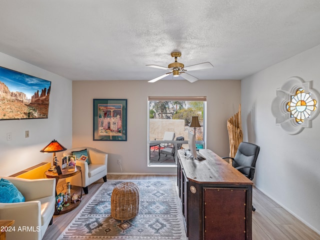 office featuring a textured ceiling, ceiling fan, and light wood-type flooring