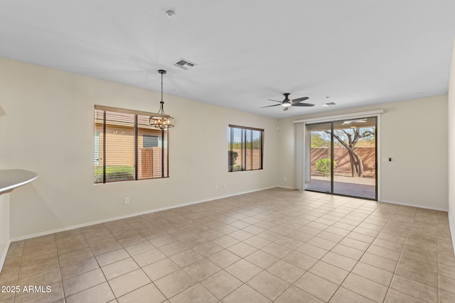 unfurnished room with light tile patterned floors, baseboards, visible vents, and ceiling fan with notable chandelier