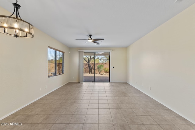 spare room with ceiling fan with notable chandelier, light tile patterned floors, and baseboards