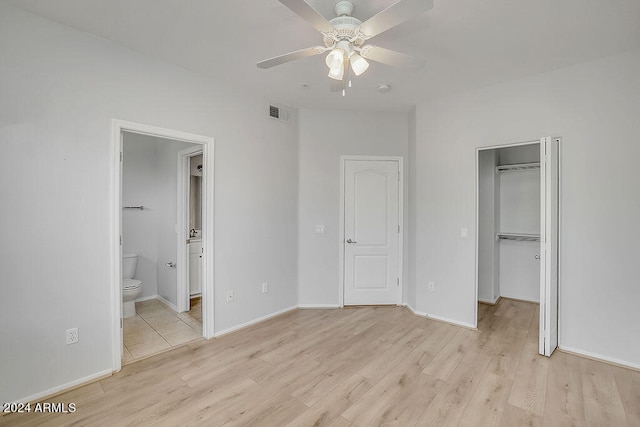 unfurnished bedroom featuring ceiling fan, light wood-type flooring, connected bathroom, and a closet