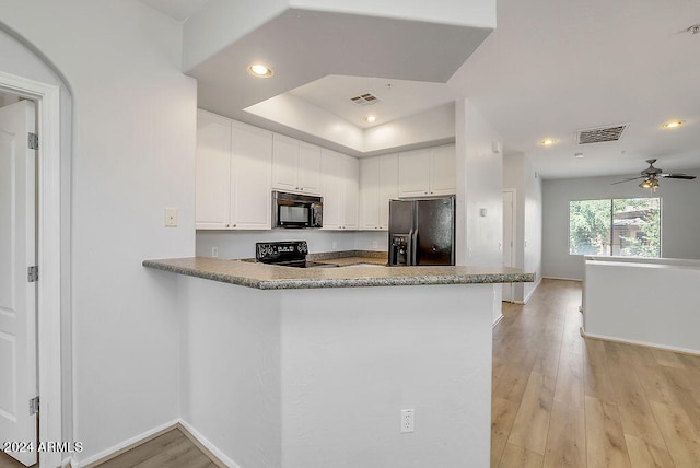 kitchen with light wood-type flooring, white cabinets, kitchen peninsula, black appliances, and ceiling fan