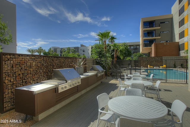 view of patio featuring a grill, a pool side deck, and an outdoor kitchen