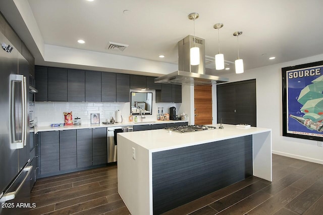 kitchen with decorative backsplash, stainless steel appliances, island range hood, a kitchen island, and hanging light fixtures