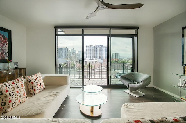 living room featuring ceiling fan and a wall of windows