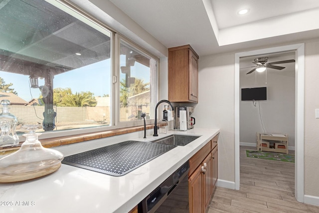 kitchen with ceiling fan, black dishwasher, sink, and light hardwood / wood-style flooring