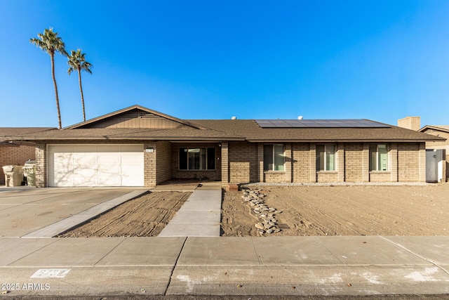 single story home with a garage and solar panels