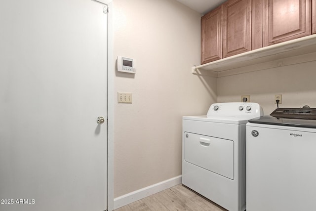 washroom with cabinets, washer and clothes dryer, and light hardwood / wood-style floors