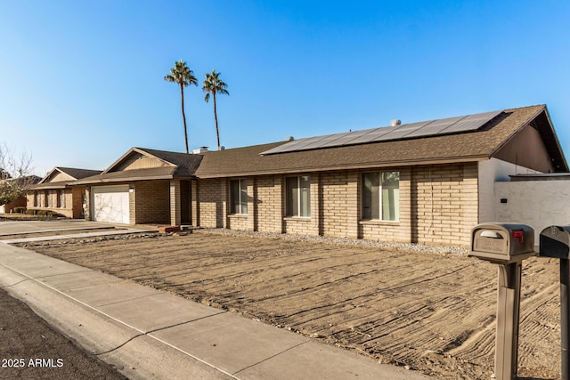 ranch-style house featuring a garage and solar panels