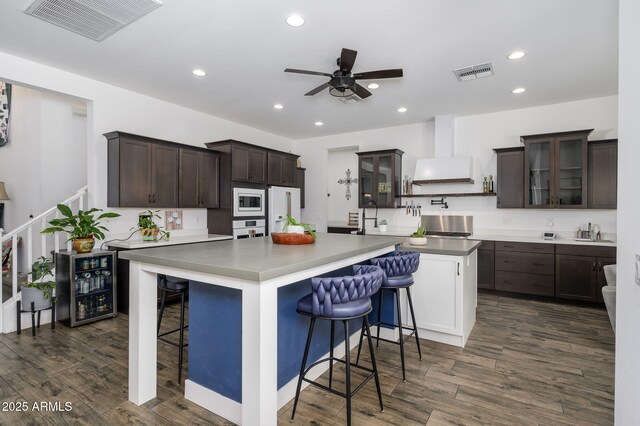 1221 E Paseo Way, Phoenix, AZ 85042 - kitchen with white appliances, wall chimney exhaust hood, a large island, dark brown cabinets, and recessed lighting