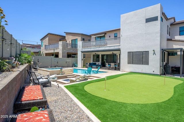 1221 E Paseo Way, Phoenix, AZ 85042 - rear view of house featuring a balcony, a putting green, a patio, an outdoor hot tub, and a fenced backyard