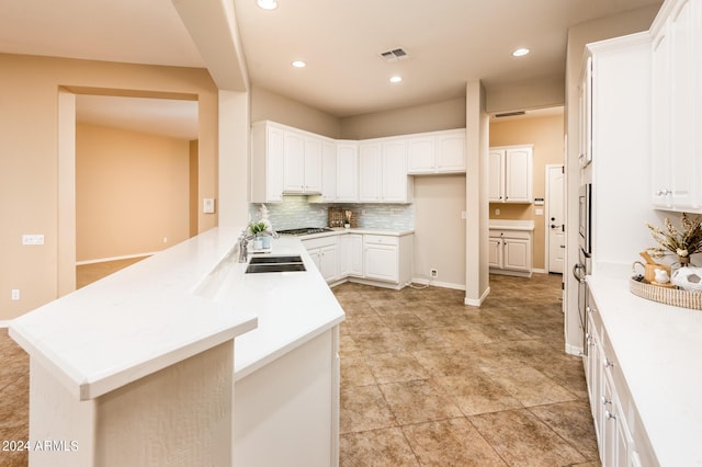 kitchen featuring sink, white cabinetry, decorative backsplash, kitchen peninsula, and stainless steel gas stovetop