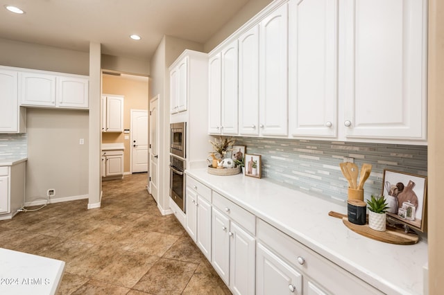 kitchen featuring decorative backsplash, white cabinets, and appliances with stainless steel finishes