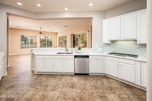 kitchen with sink, appliances with stainless steel finishes, kitchen peninsula, decorative backsplash, and white cabinets