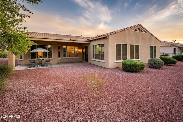 back house at dusk with a patio area