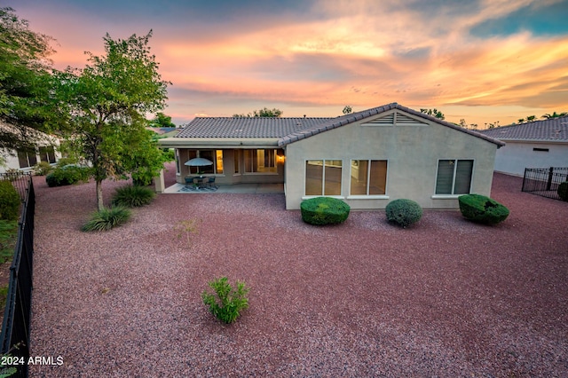 back house at dusk featuring a patio