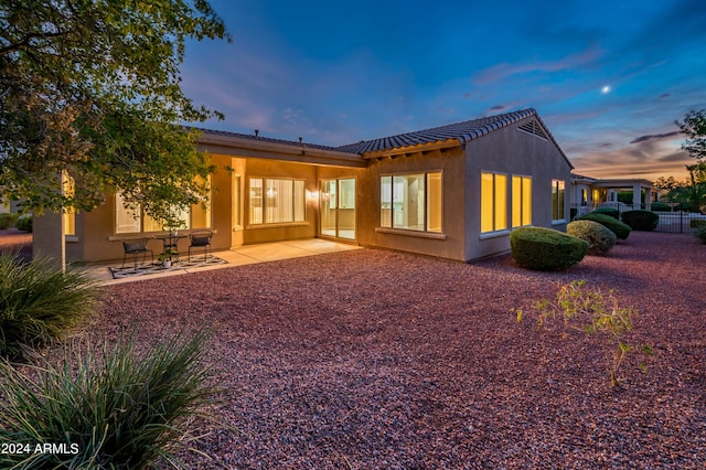 back house at dusk with a patio area