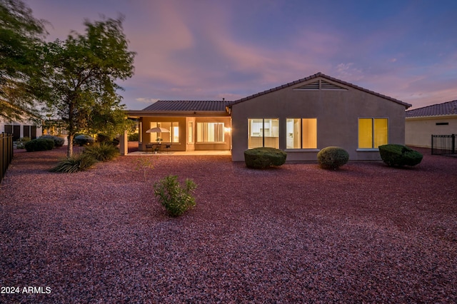 back house at dusk with a patio area