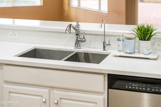 kitchen featuring dishwasher, sink, and white cabinets