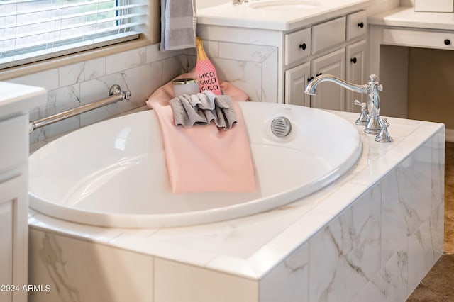 bathroom with a relaxing tiled tub and sink