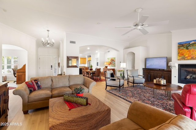 living room featuring crown molding, lofted ceiling, ceiling fan with notable chandelier, and light wood-type flooring