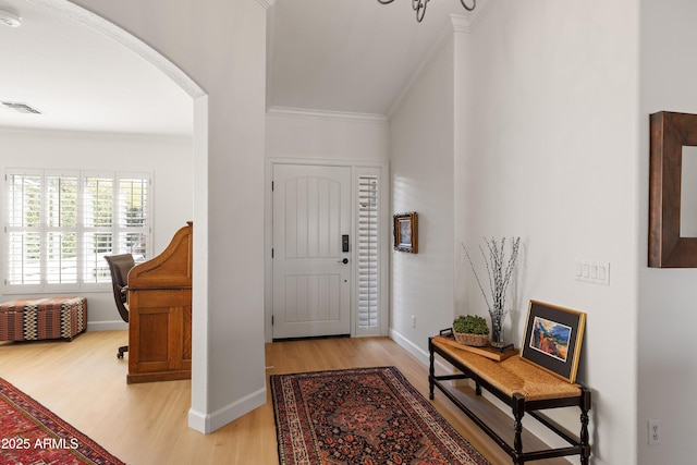 foyer entrance with crown molding and light hardwood / wood-style floors