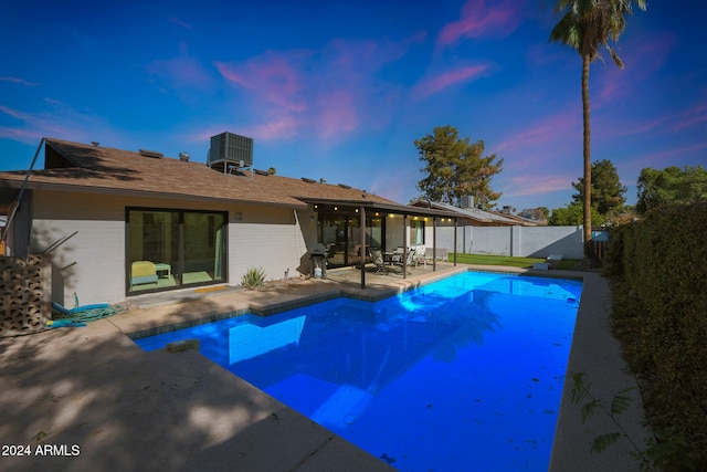 pool at dusk featuring a patio and central air condition unit