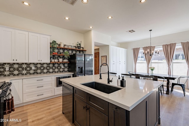 kitchen with light hardwood / wood-style flooring, hanging light fixtures, sink, white cabinetry, and appliances with stainless steel finishes