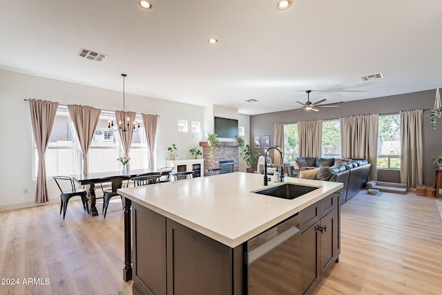 kitchen with sink, dishwasher, ceiling fan with notable chandelier, light hardwood / wood-style floors, and pendant lighting