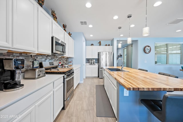 kitchen with a center island with sink, decorative backsplash, a kitchen breakfast bar, and stainless steel appliances