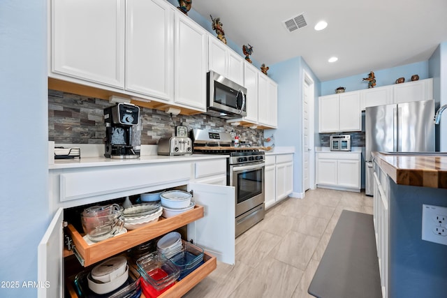 kitchen featuring tasteful backsplash, butcher block counters, white cabinets, and appliances with stainless steel finishes