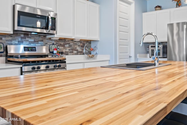 kitchen featuring appliances with stainless steel finishes, backsplash, white cabinetry, and sink