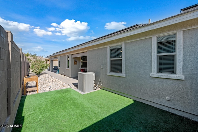 exterior space with a patio area, a yard, and central AC