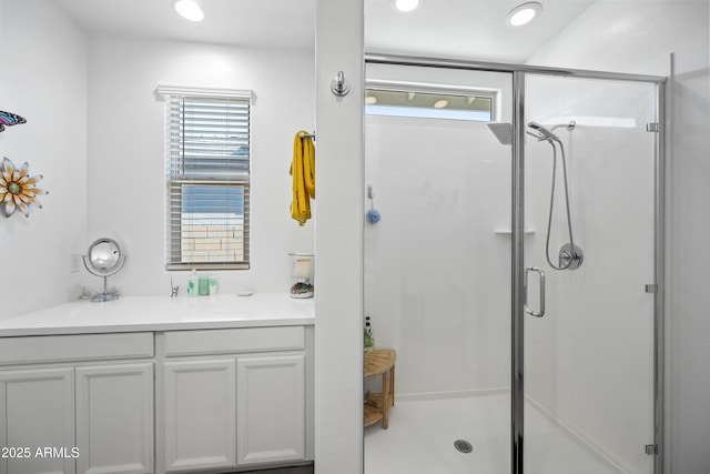 bathroom featuring a shower with door and vanity