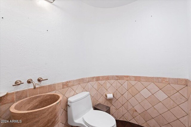 bathroom with tile walls and toilet