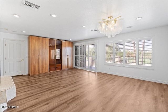 unfurnished living room featuring hardwood / wood-style flooring and a chandelier